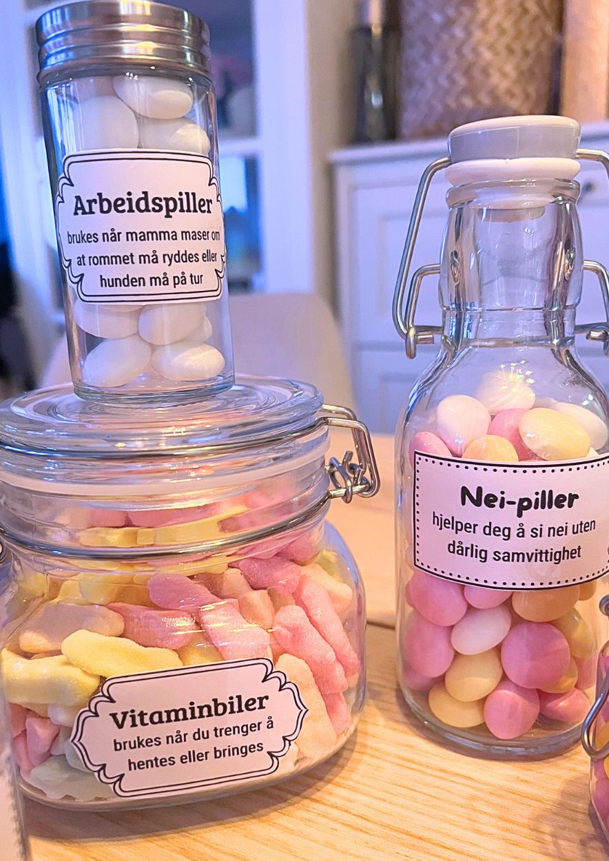 Tre godterifylte glasskrukker med etikettene «Arbeidspiller», «Nei-piller» og «Vitaminbiler»
