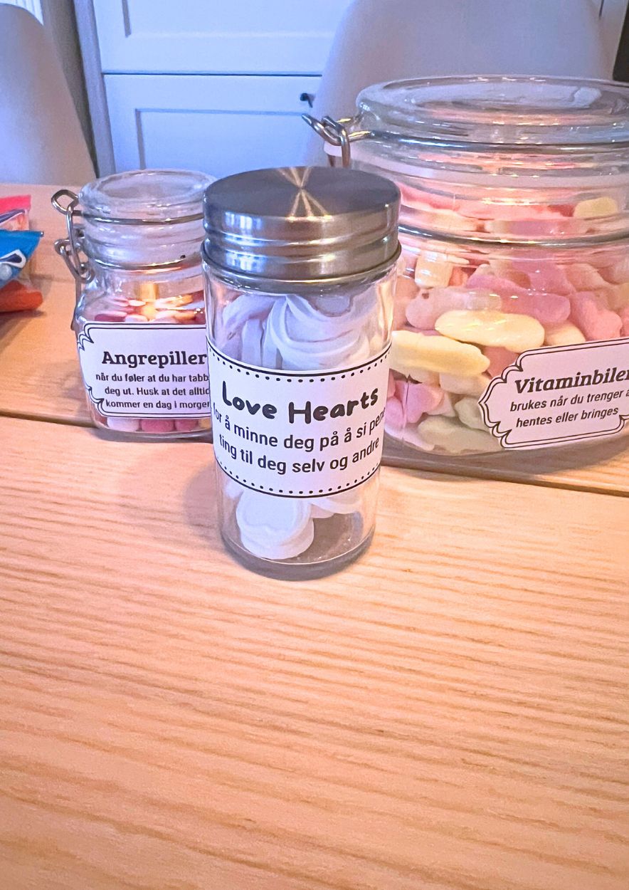 Lite glassrør med Love Hearts foran glasskrukker merket «Angrepiller» og «Vitaminbiler»